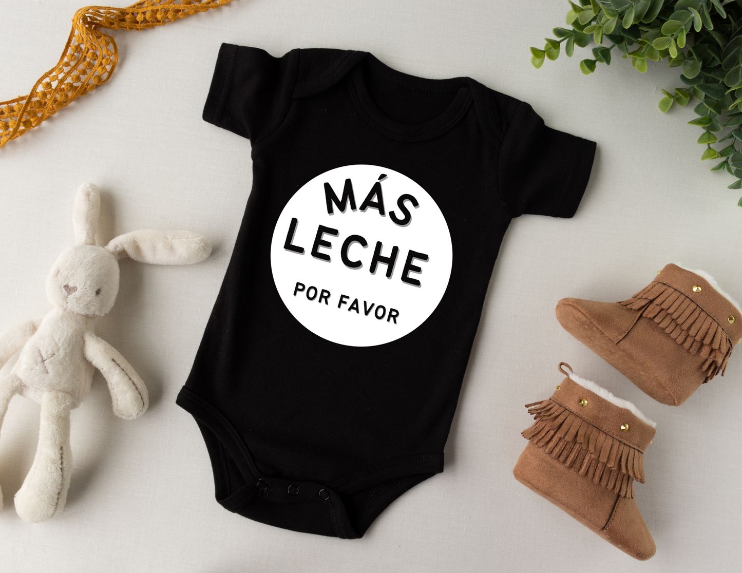 Black Baby Bodysuit with White Circle Across the Belly and Chest that says Mas Leche Por Favor